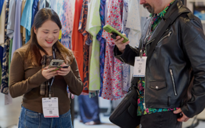 Fashion buyers using phones beside apparel displays at the Las Vegas Marketplace