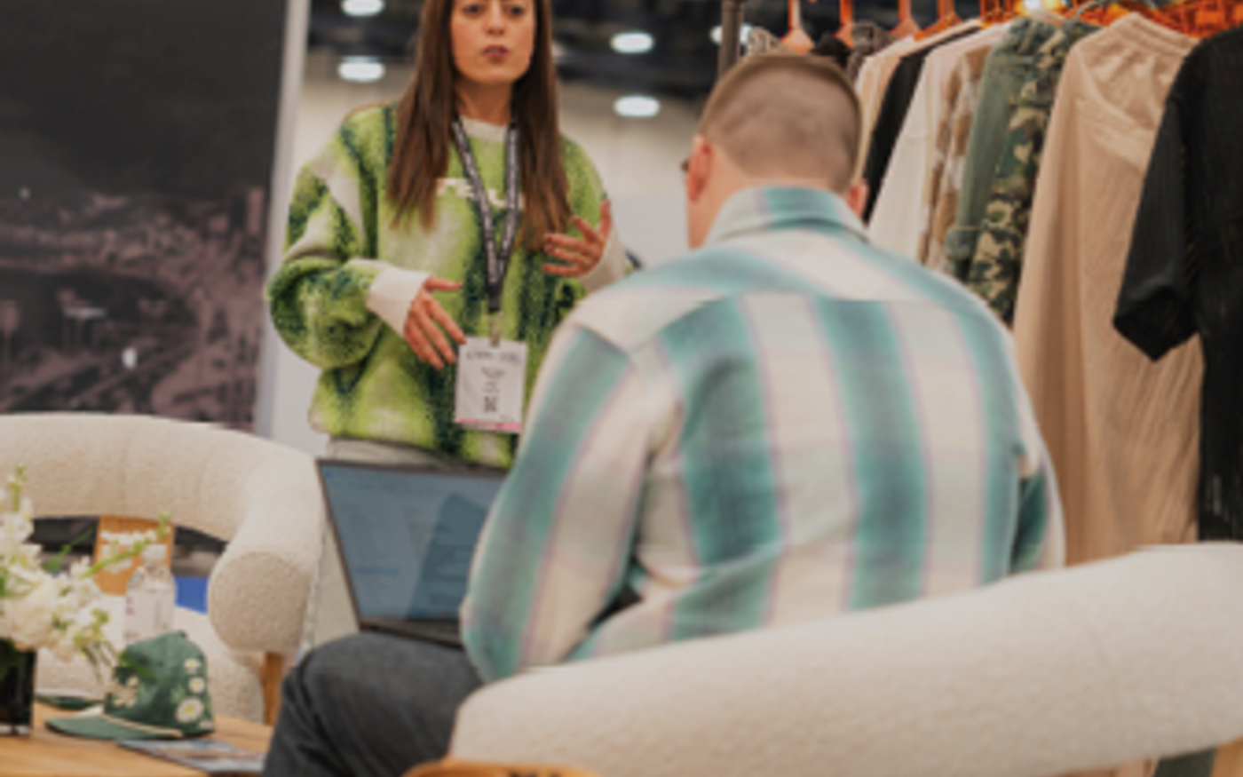 Fashion brand representative meeting with a buyer beside apparel racks
