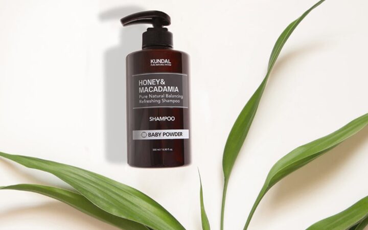 KUNDAL Honey and Macadamia shampoo bottle arranged with green leaves