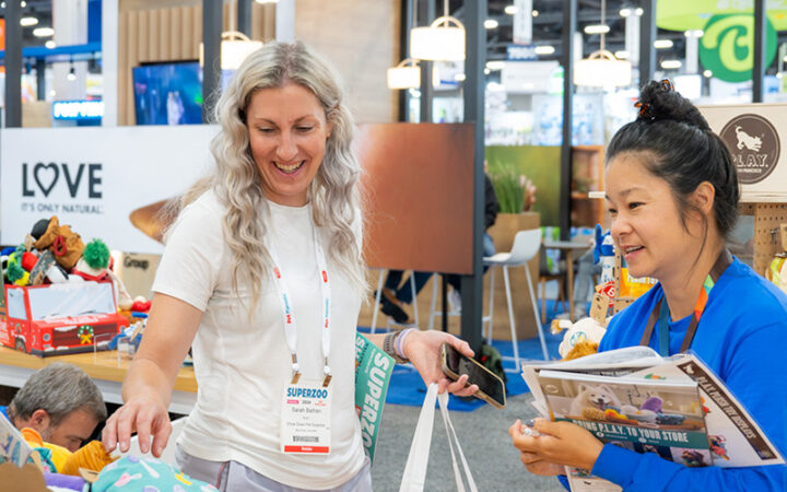 A buyer reviews a pet wellness product at a SUPERZOO exhibit