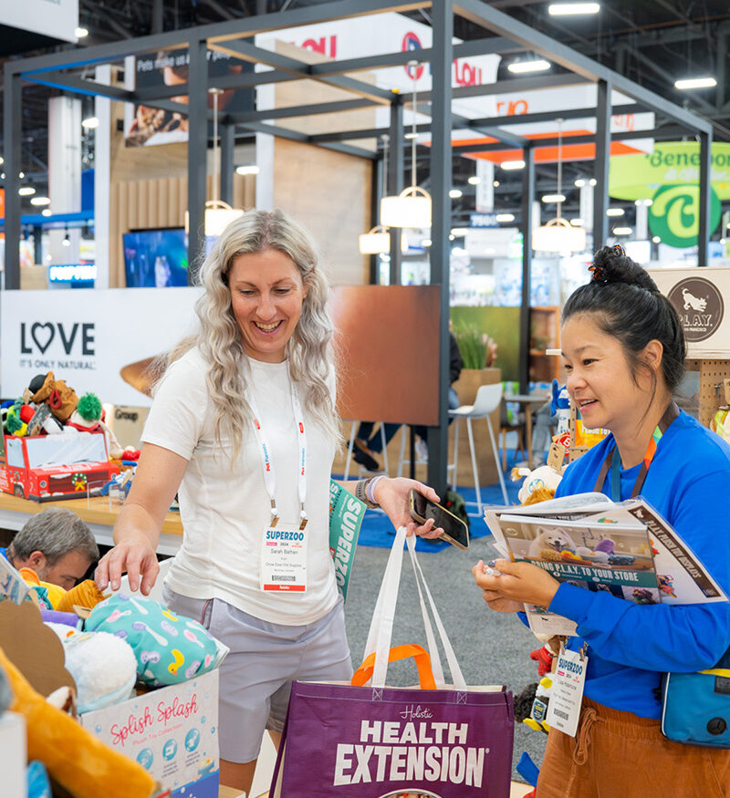 A buyer reviews a pet wellness product at a SUPERZOO exhibit